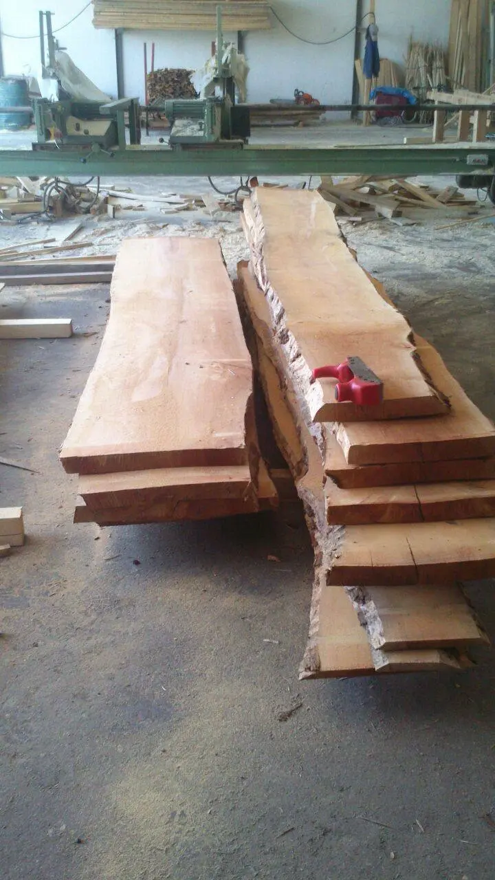 Frisch aufgeschnittene massive Holzbohlen mit natürlicher Waldkante in der Werkstatt