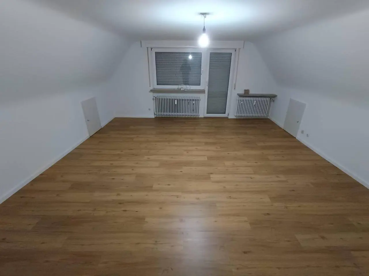 Heller Dachgeschossraum mit neu verlegtem, durchgehendem Boden in warmer Holzoptik
