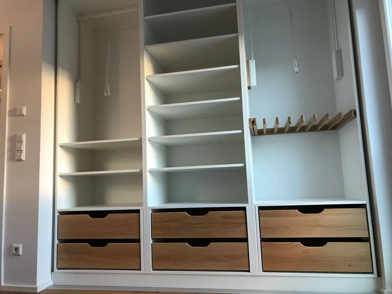 Raumhoher weißer Einbauschrank mit offenen Fächern und Schubladenfronten aus Holz