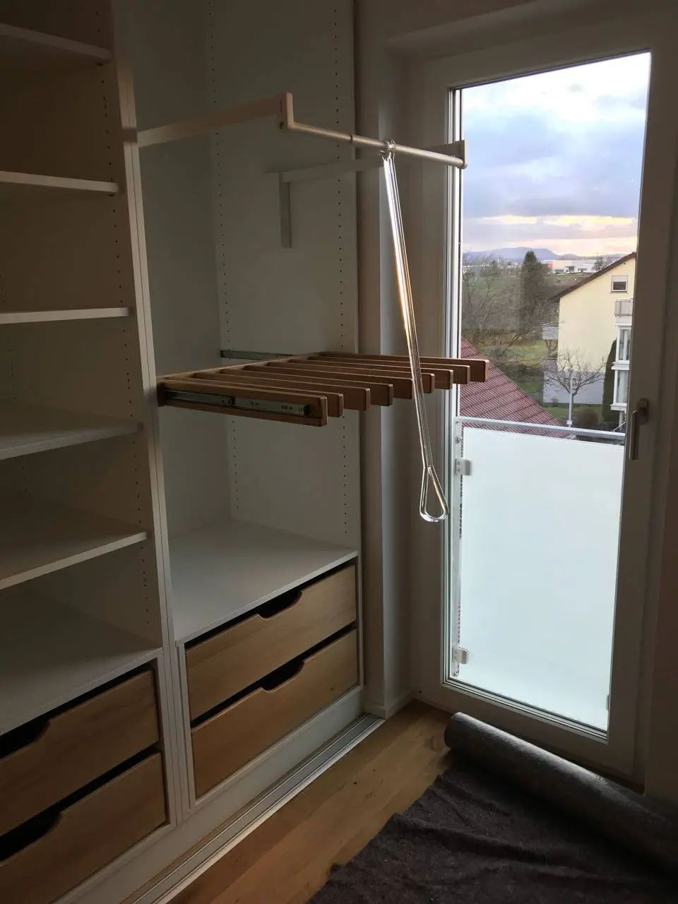 Heruntergezogene Kleiderstange und Holzauszug in einem raumhohen Einbauschrank
