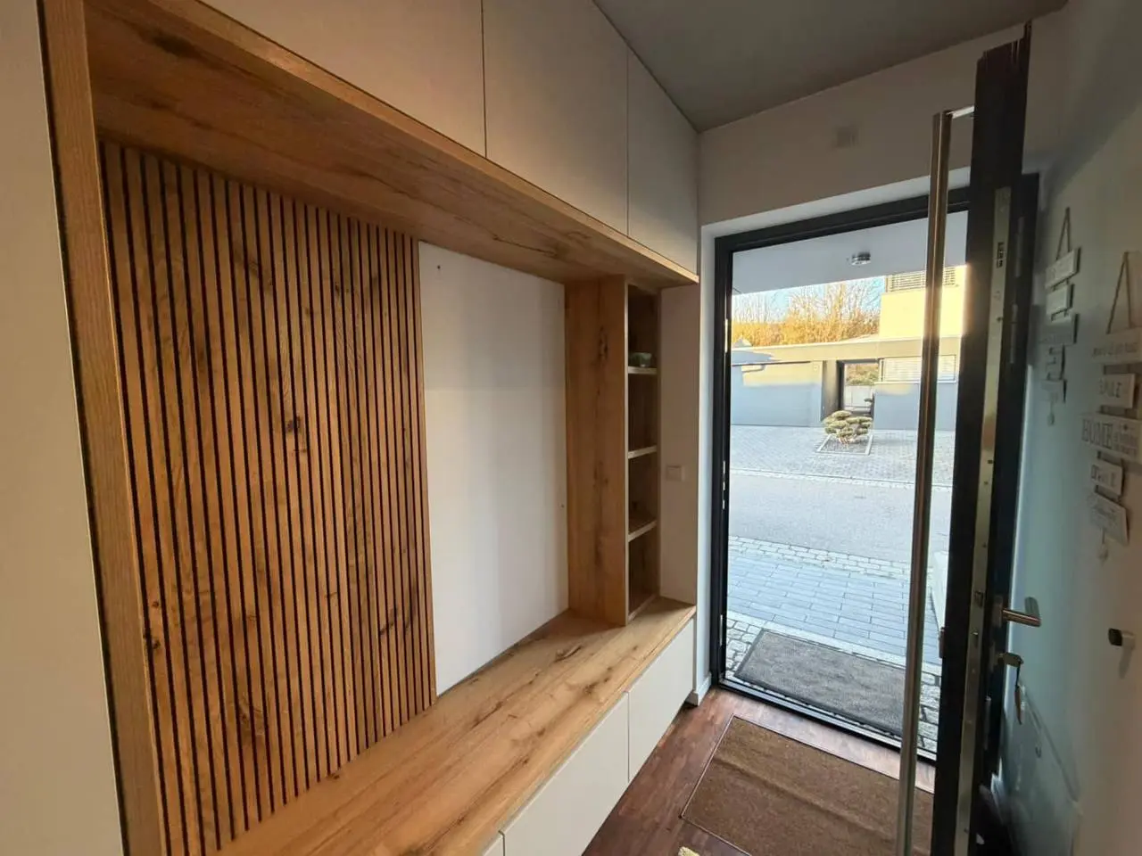 Flurgarderobe mit Sitzbank, deckenhohem Stauraum und Lamellenfläche direkt neben der Haustür
