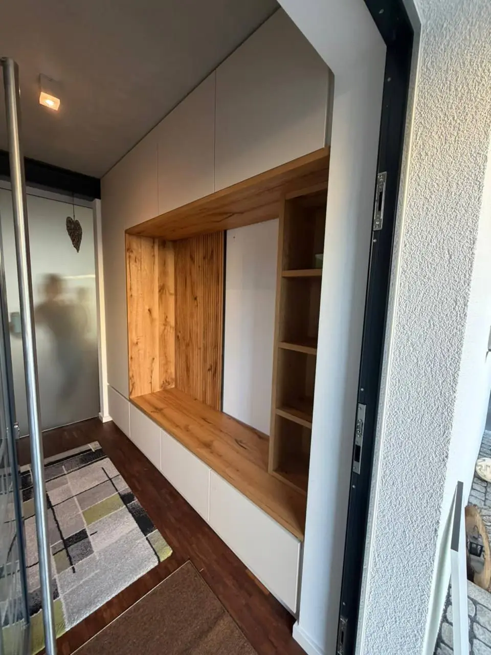 Maßgefertigte Flurgarderobe mit warmer Holz-Sitznische, weißen Fronten und offenen Seitenfächern