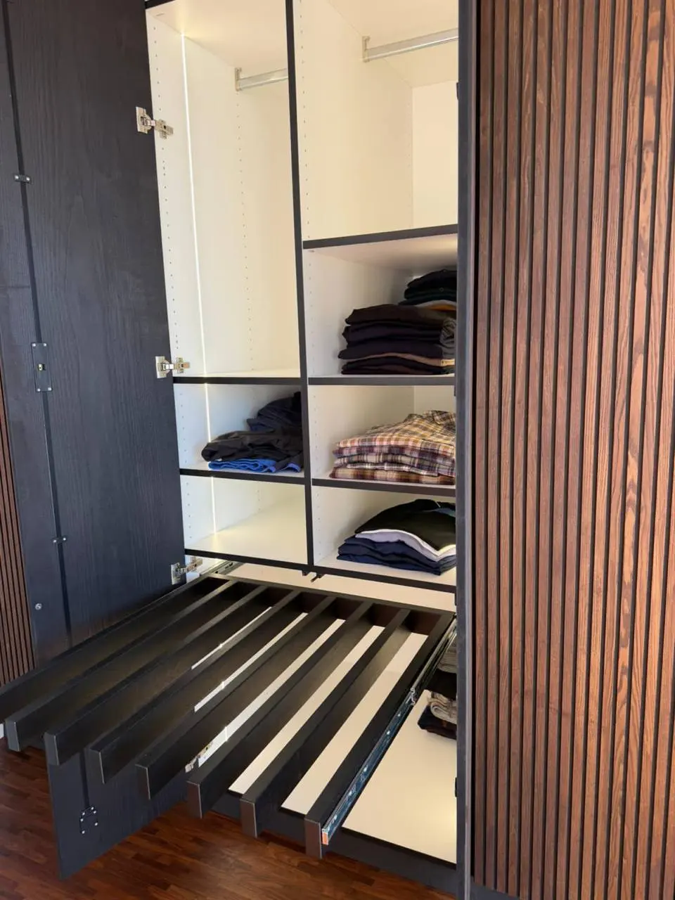 Weit herausgezogener Hosenhalter in einem individuell aufgeteilten Einbauschrank